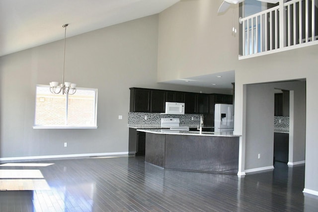 kitchen featuring high vaulted ceiling, dark hardwood / wood-style floors, kitchen peninsula, white appliances, and decorative backsplash