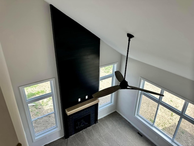 unfurnished living room featuring ceiling fan, a fireplace, carpet floors, and high vaulted ceiling