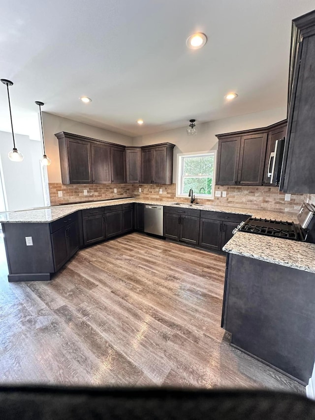 kitchen featuring dark brown cabinetry, stainless steel appliances, hanging light fixtures, and sink