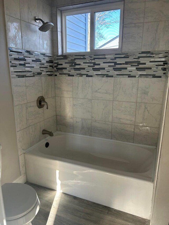 bathroom featuring hardwood / wood-style floors, toilet, and tiled shower / bath