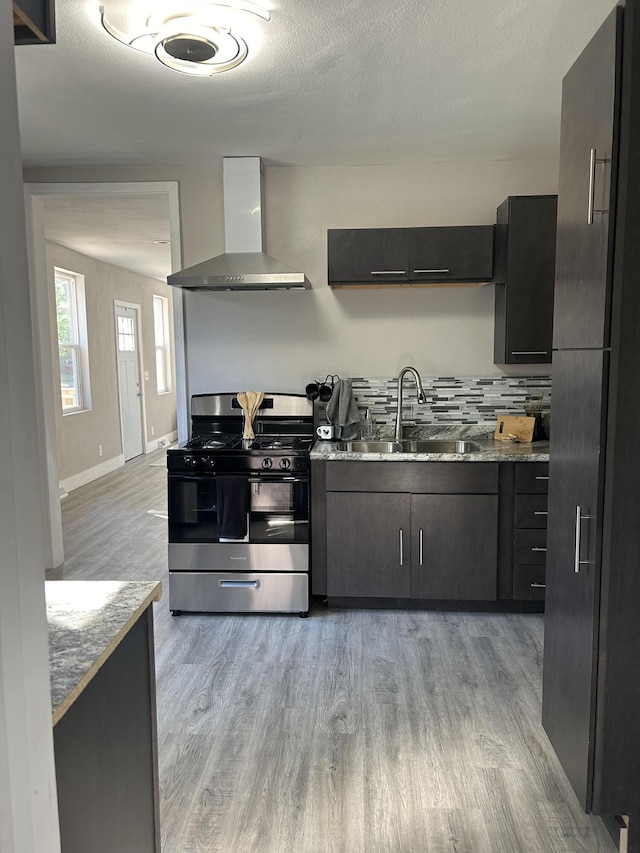 kitchen featuring light wood-type flooring, sink, stainless steel range with gas cooktop, and wall chimney range hood