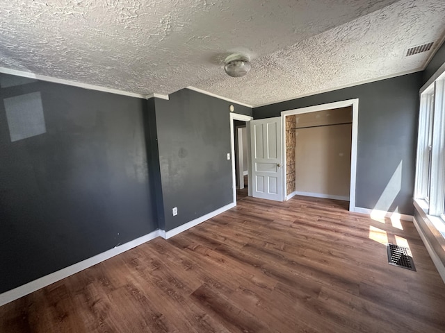 unfurnished bedroom featuring crown molding, hardwood / wood-style flooring, and a textured ceiling