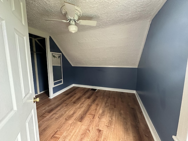 additional living space featuring ceiling fan, a textured ceiling, vaulted ceiling, and wood-type flooring