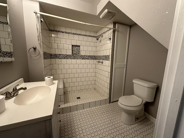 bathroom featuring vanity, toilet, tile patterned flooring, and a tile shower