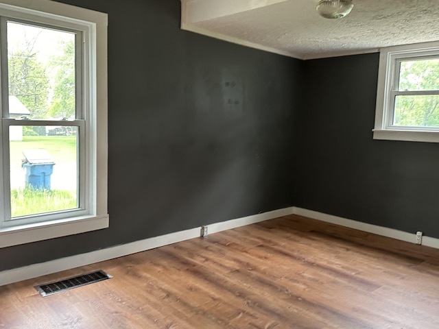 empty room with hardwood / wood-style flooring and a textured ceiling