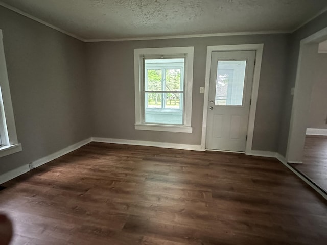 doorway with dark wood-type flooring, ornamental molding, and a textured ceiling