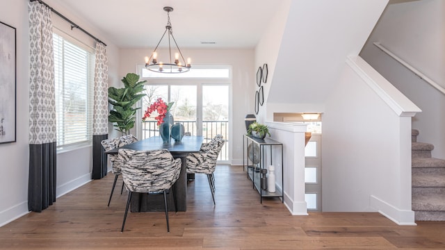 dining space featuring dark wood-type flooring and an inviting chandelier