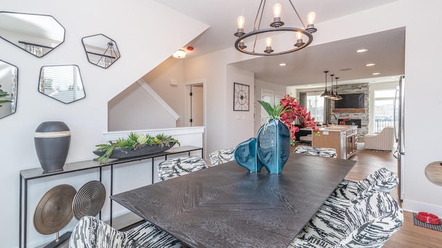 dining area featuring light wood-type flooring, sink, a notable chandelier, and a fireplace