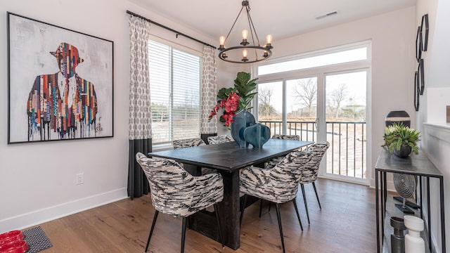 dining space with hardwood / wood-style flooring and an inviting chandelier