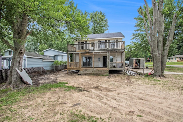 rear view of house featuring a wooden deck and a storage unit