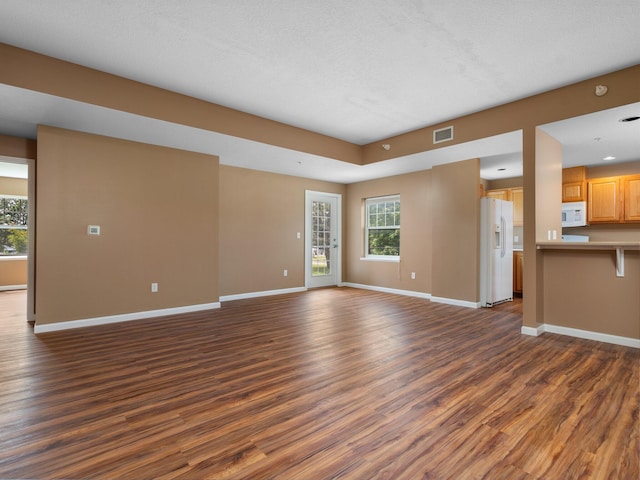 unfurnished living room with dark hardwood / wood-style flooring, plenty of natural light, and a textured ceiling