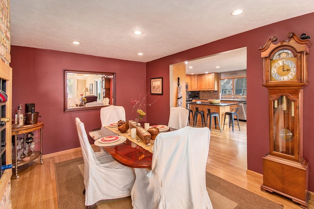 dining area with light hardwood / wood-style flooring and a textured ceiling