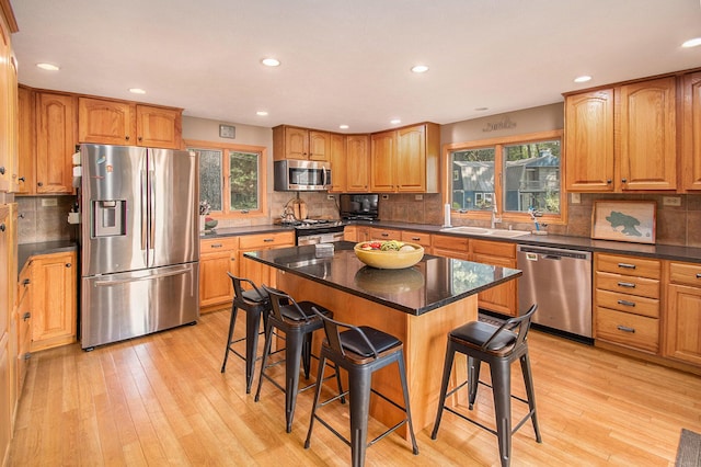 kitchen with light wood-type flooring, stainless steel appliances, a breakfast bar, and a kitchen island