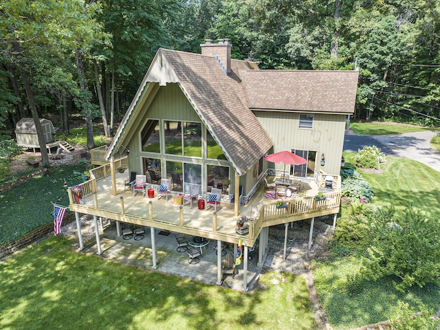 rear view of house with a wooden deck and a lawn