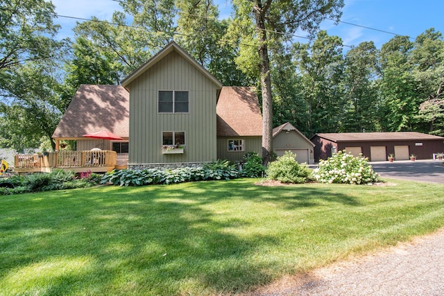 exterior space featuring a wooden deck, a garage, an outdoor structure, and a front yard