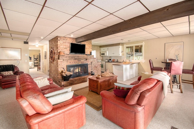 living room featuring beamed ceiling, light colored carpet, and a fireplace