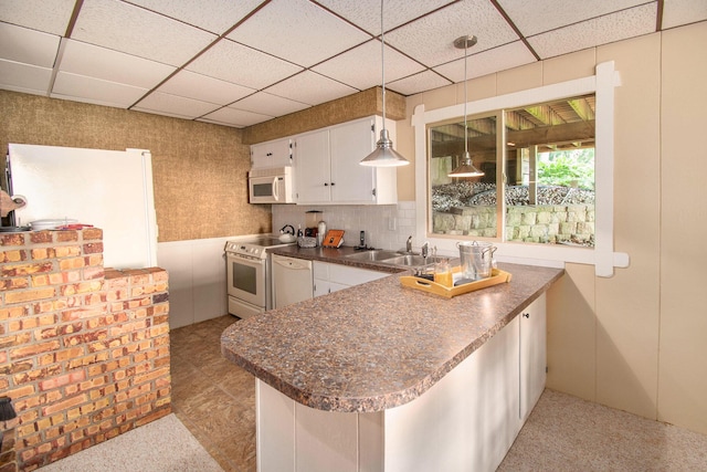 kitchen featuring sink, white appliances, hanging light fixtures, white cabinets, and kitchen peninsula