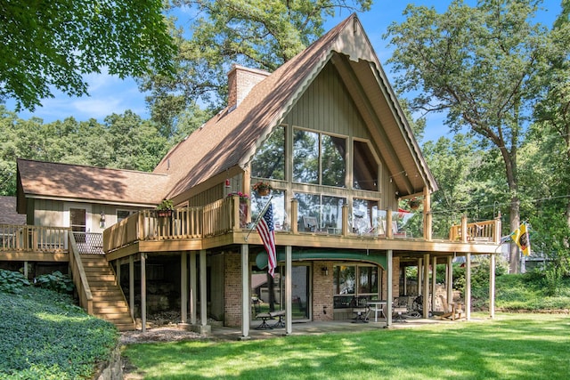 rear view of property featuring a wooden deck, a patio area, and a lawn