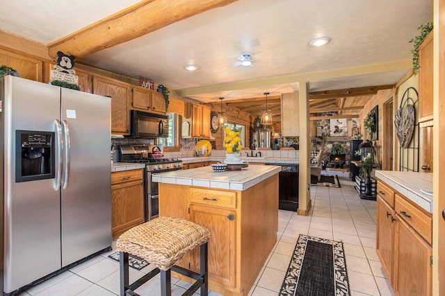 kitchen featuring pendant lighting, light tile patterned floors, black appliances, a kitchen island, and tile countertops