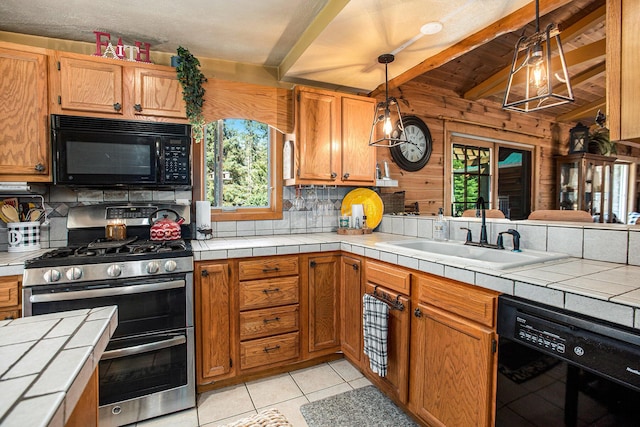 kitchen featuring hanging light fixtures, light tile patterned floors, tile countertops, and black appliances