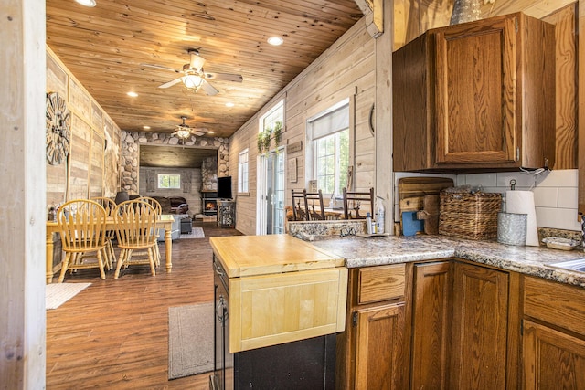 kitchen with dark wood-type flooring, wooden ceiling, and wood walls