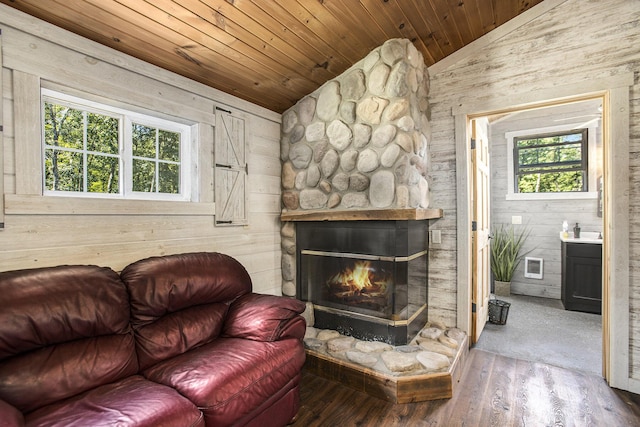 living room with wood ceiling, hardwood / wood-style floors, wooden walls, a stone fireplace, and vaulted ceiling