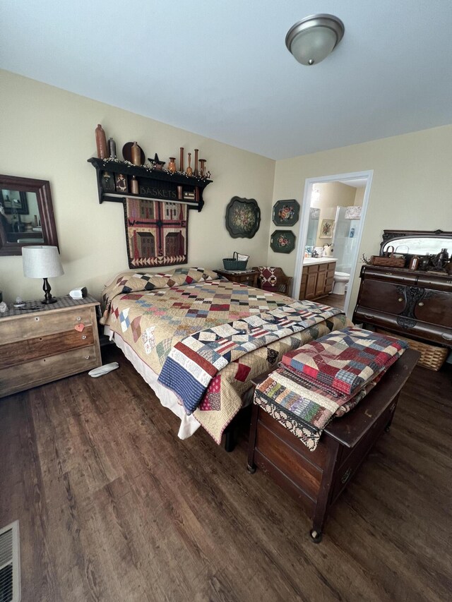 bedroom with ensuite bathroom and hardwood / wood-style floors