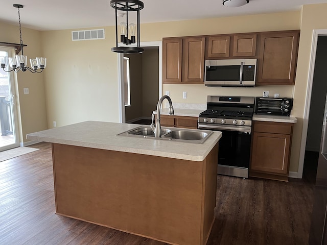 kitchen featuring sink, dark hardwood / wood-style floors, an island with sink, pendant lighting, and appliances with stainless steel finishes