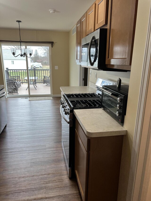 kitchen featuring hardwood / wood-style flooring, decorative light fixtures, appliances with stainless steel finishes, and a notable chandelier