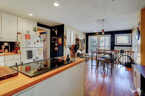 kitchen with light wood-type flooring, black electric cooktop, decorative light fixtures, white fridge, and white cabinetry