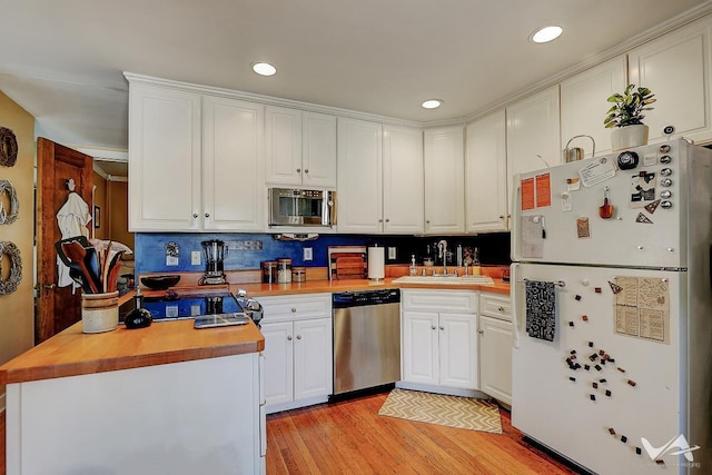 kitchen with wooden counters, stainless steel dishwasher, sink, white fridge, and white cabinetry