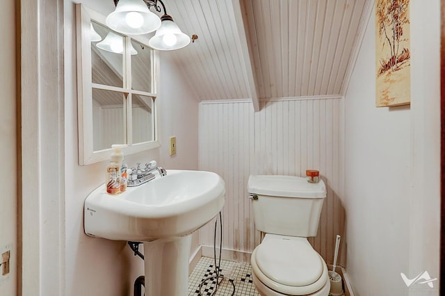 bathroom with tile patterned floors, wooden walls, wooden ceiling, beamed ceiling, and toilet