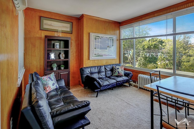 carpeted living room featuring radiator and wood walls