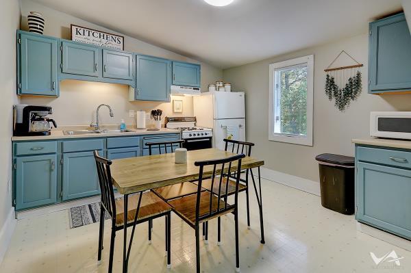 kitchen with lofted ceiling, white appliances, exhaust hood, sink, and blue cabinetry