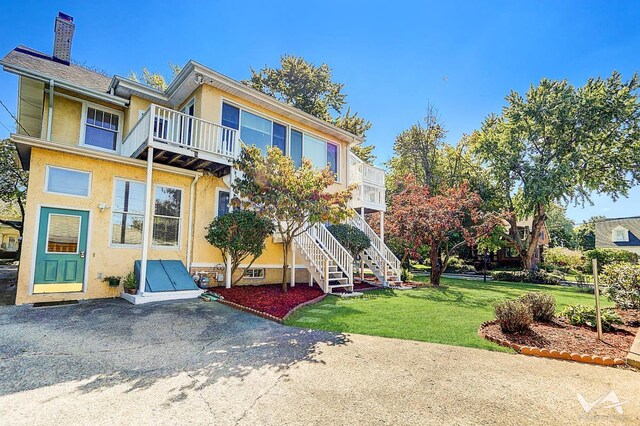 view of front of property featuring a balcony and a front yard