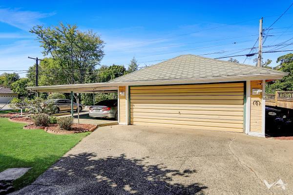 garage with a carport and a lawn