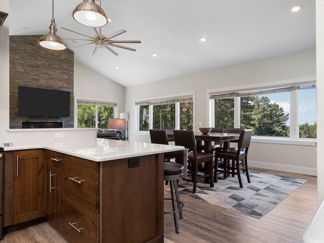 kitchen featuring vaulted ceiling, a kitchen bar, light hardwood / wood-style floors, and decorative light fixtures