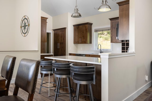 kitchen featuring pendant lighting, sink, dark hardwood / wood-style floors, a kitchen bar, and kitchen peninsula