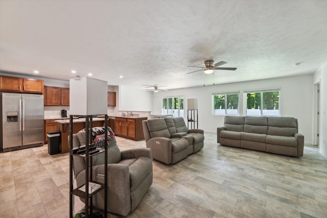 living room featuring ceiling fan, a healthy amount of sunlight, a textured ceiling, and light hardwood / wood-style flooring