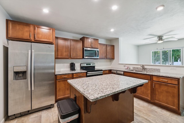 kitchen with appliances with stainless steel finishes, light wood-type flooring, a breakfast bar area, and sink