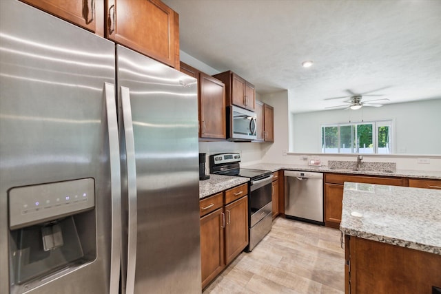 kitchen with light stone countertops, a textured ceiling, stainless steel appliances, ceiling fan, and sink