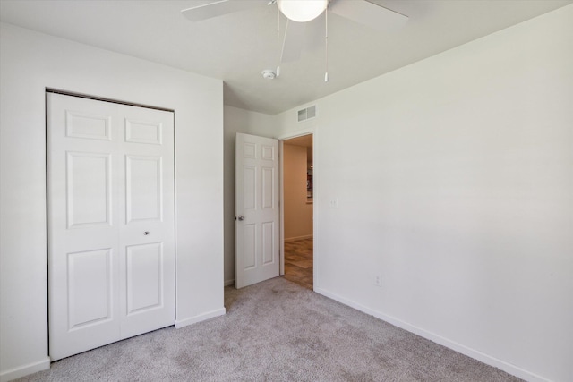 unfurnished bedroom with ceiling fan, a closet, and light carpet