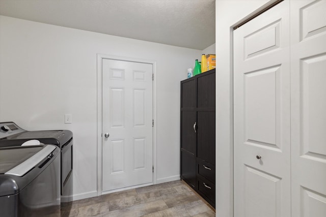 laundry area featuring cabinets, a textured ceiling, light hardwood / wood-style floors, and washer and clothes dryer