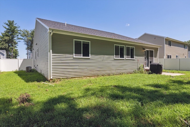 rear view of house featuring central AC and a yard