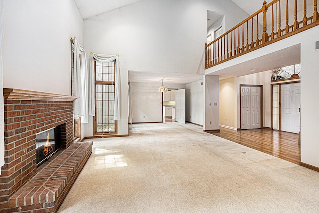 unfurnished living room with a brick fireplace, carpet, and high vaulted ceiling