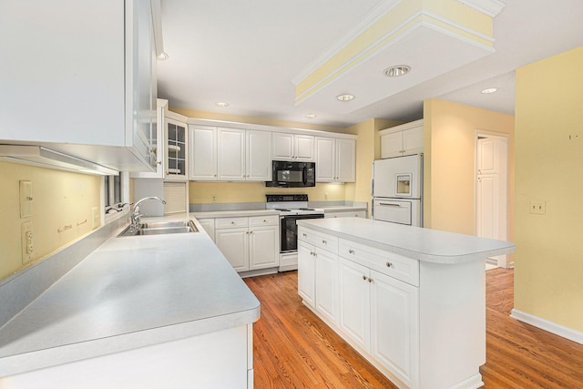 kitchen featuring sink, white appliances, light hardwood / wood-style flooring, white cabinets, and a kitchen island