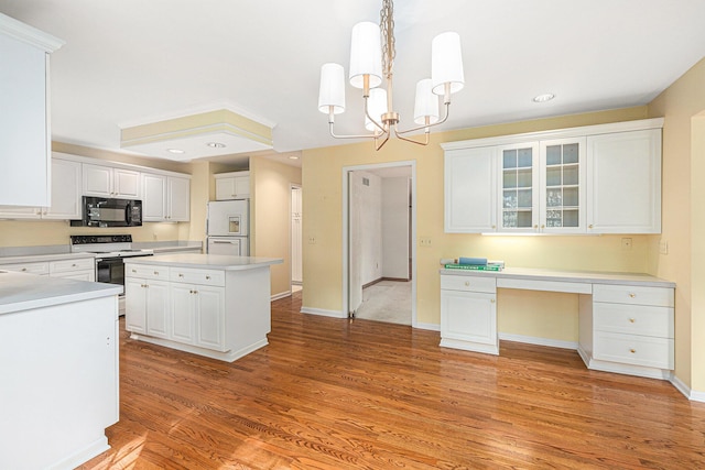 kitchen with a kitchen island, built in desk, decorative light fixtures, white cabinets, and white appliances