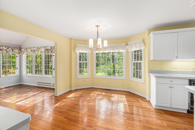 unfurnished dining area featuring lofted ceiling, a healthy amount of sunlight, a notable chandelier, and baseboard heating