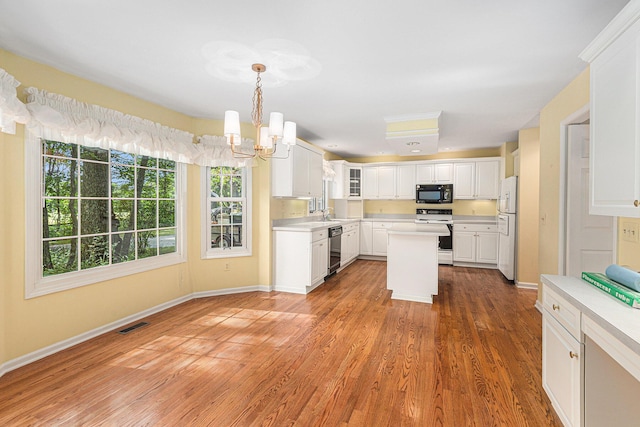 kitchen featuring a kitchen island, wood-type flooring, white cabinets, hanging light fixtures, and black appliances