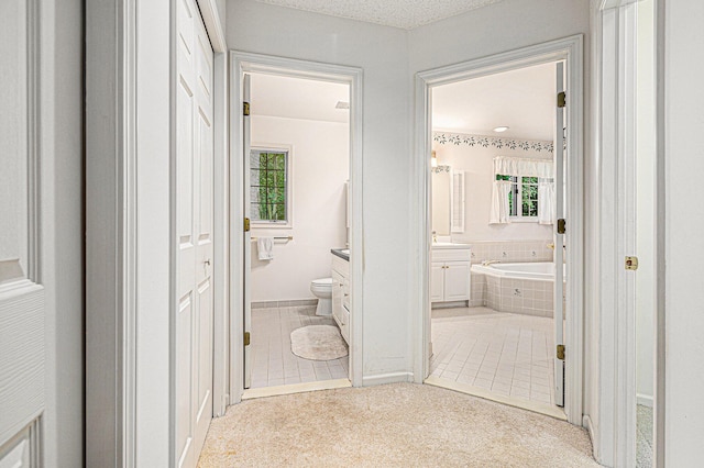 bathroom with vanity, tiled bath, and toilet